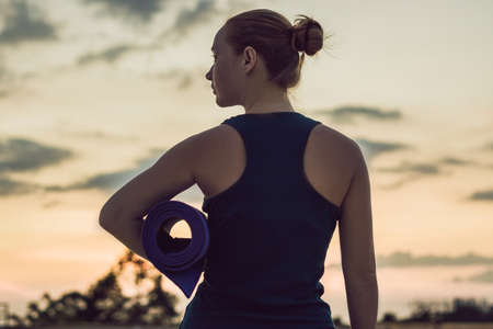 Woman with mat ready to against the sunset.の写真素材