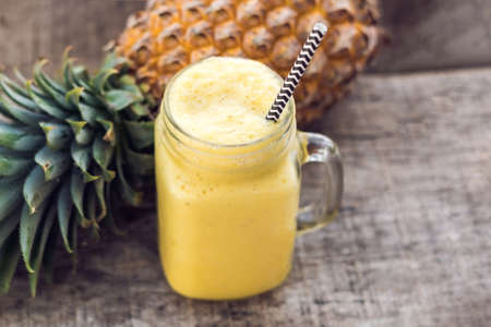 Pineapple smoothie with fresh pineapple on wooden table.の写真素材