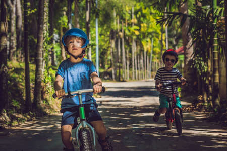 Two little boys children having fun on Balance Bike on a country tropical road.の写真素材