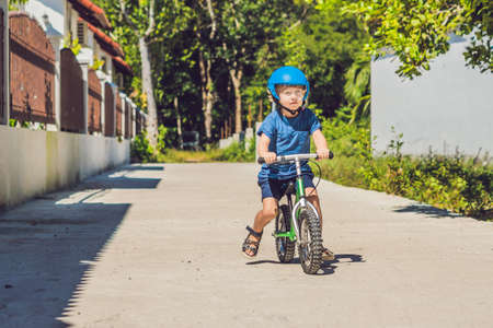 Little boy on a bicycle. Caught in motion, on a driveway motion blurred. Preschool child's first day on the bike. The joy of movement. Little athlete learns to keep balance while riding a bicycle.の写真素材