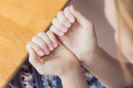 Closeup finger nail care by manicure specialist in beauty salon. Manicurist paints nails with nail polish.の写真素材