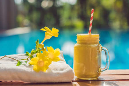 Mango smoothies on the background of the pool. Fruit smoothie - healthy eating concept. Close up of detox smoothie with mango.の写真素材