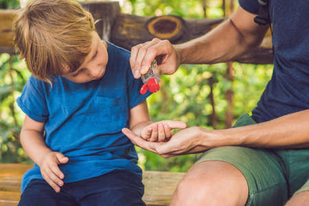 Father and son using wash hand sanitizer gel in the park before a snack.の写真素材