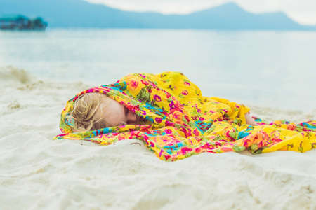 Adorable baby boy, sleeping on the beach, exhausted after fun day at the beach.の写真素材
