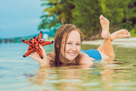 Young woman in the sea with red starfishes.の写真素材