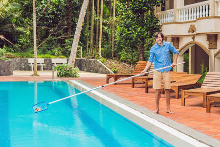 Cleaner of the swimming pool . Man in a blue shirt with cleaning equipment for swimming pools,...
