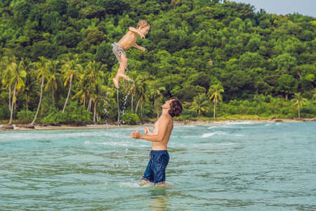 Dad plays with his son in the sea.の写真素材