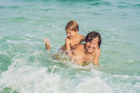 Dad plays with his son in the sea.の写真素材