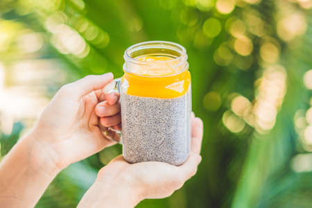 Chia seed pudding with almond milk and fresh mango topping in hand.の写真素材