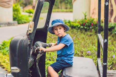 A boy on an old tricycle in the park.