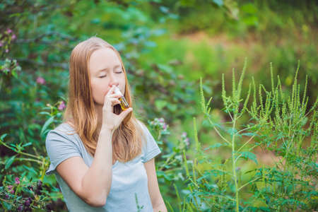 Young woman uses a spray from an allergy because of an allergy to ragweed.の写真素材