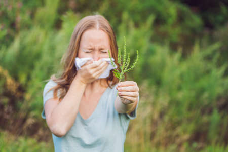 Young woman sneezes because of an allergy to ragweed.の写真素材