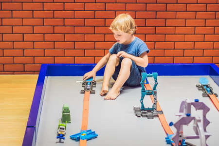 A boy is playing with a toy railroad.