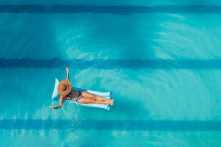 Enjoying suntan. Vacation concept. Top view of slim young woman in bikini on the blue air mattress...