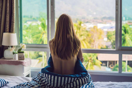 young happy woman woke up in the morning in the bedroom by the window with beautiful mountain views.の写真素材