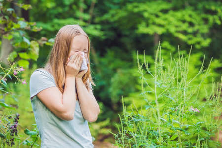 Young woman sneezes because of an allergy to ragweed.の写真素材