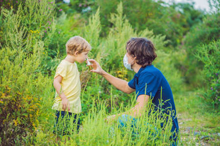 Father and son use a spray from an allergy because of an allergy to ragweed.の写真素材