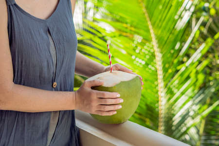 coconut in beautiful female hands on a green background. The Benefits of Coconut Water Concept.の写真素材