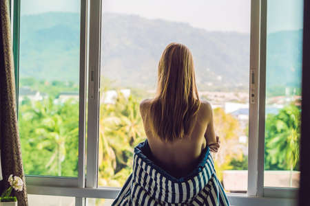 young happy woman woke up in the morning in the bedroom by the window with beautiful mountain views.の写真素材