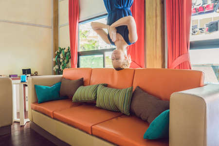 A woman stands upside down in the living room and meditates.の写真素材