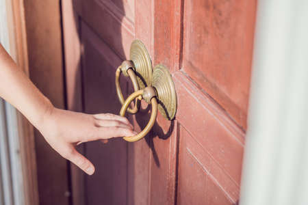 The hand opens the antique door by the round handle.の写真素材