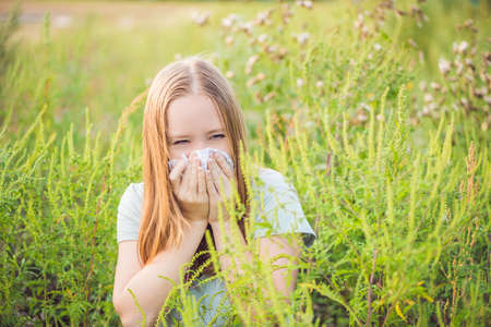 Young woman sneezes because of an allergy to ragweed.の写真素材