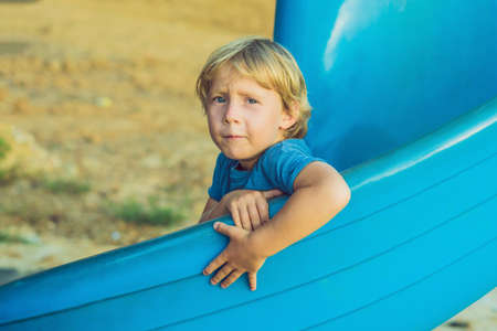 Funny toddler boy having fun on slide on playground.の写真素材