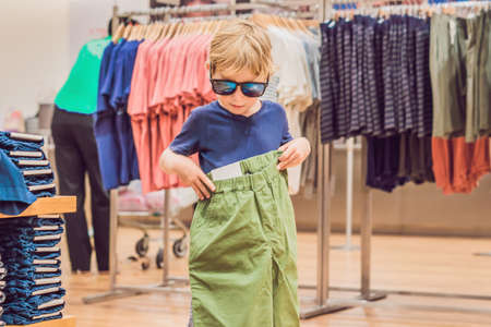 The boy tries on clothes in the childrens clothing store.の写真素材