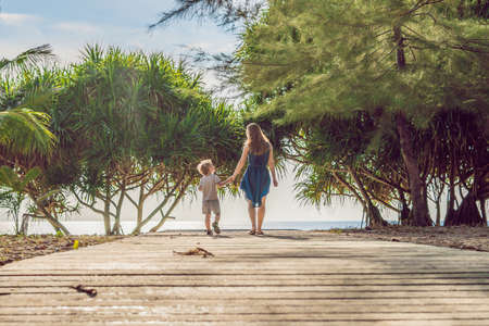 Mother and son go to the sea beach. Resort vacation on tropical beach. Path to beach.の写真素材