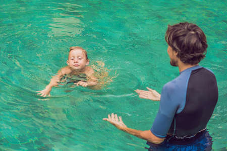 Male instructor swimming for children teaches a happy boy to swim in the pool.の写真素材