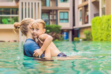 Woman swimming instructor for children is teaching a happy boy to swim in the pool.の写真素材