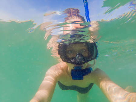 Woman snorkeling in tropical waters in front of exotic island.の写真素材