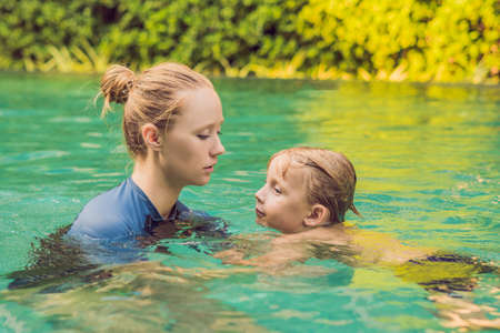 Woman swimming instructor for children is teaching a happy boy to swim in the pool.の写真素材