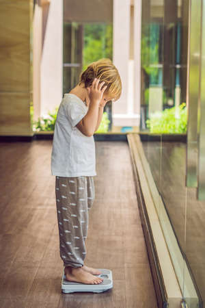 The boy stands on the scales to find out his weight.の写真素材