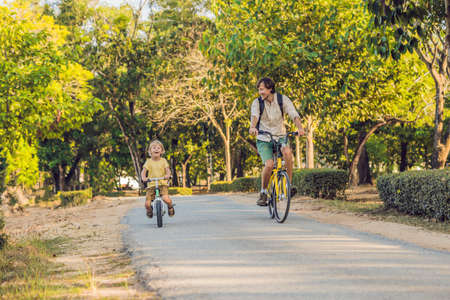 Happy family is riding bikes outdoors and smiling. Father on a bike and son on a balancebike.