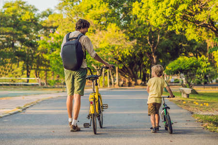 Happy family is riding bikes outdoors and smiling. Father on a bike and son on a balancebike.の写真素材