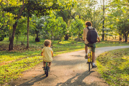 Happy family is riding bikes outdoors and smiling. Father on a bike and son on a balancebike.