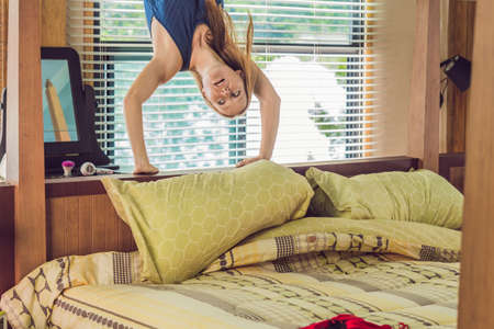 Happy smiling woman upside down in bed in the bedroom.の写真素材