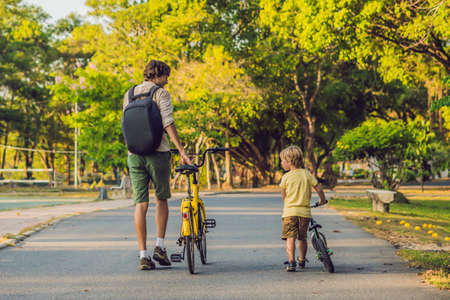 Happy family is riding bikes outdoors and smiling. Father on a bike and son on a balancebike.の写真素材