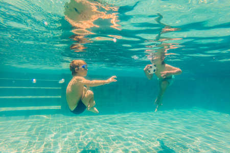 two children diving in masks underwater in pool.の写真素材