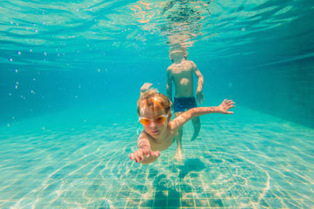 two children diving in masks underwater in pool.の写真素材