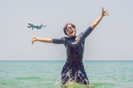 A man bathes in the sea, an airplane lands.の写真素材
