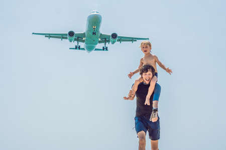 Father and son have fun on the beach watching the landing planes. Traveling on an airplane with...