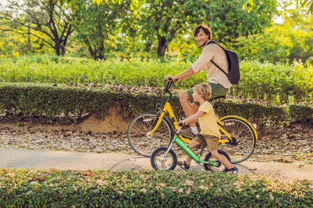 Happy family is riding bikes outdoors and smiling. Father on a bike and son on a balancebike.の写真素材