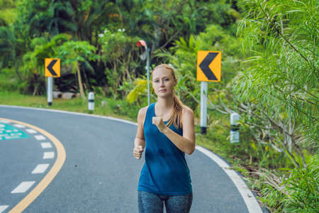 Sporty woman running on road at sunrise. Fitness and workout wellness concept.の写真素材