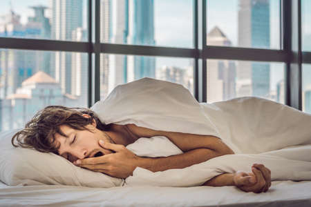 Man wakes up in the morning in an apartment in the downtown area with a view of the skyscrapers....