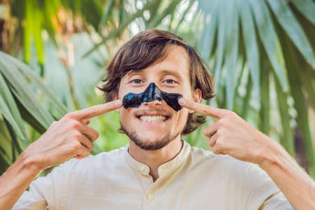 Happy man with black mask on the face. Photo man receiving spa treatments. Beauty Skin care concept.