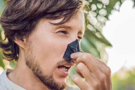 Happy man with black mask on the face. Photo man receiving spa treatments. Beauty Skin care concept.の写真素材