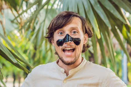 Happy man with black mask on the face. Photo man receiving spa treatments. Beauty Skin care concept.