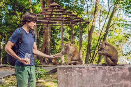 The man feeds the monkey whith nuts.